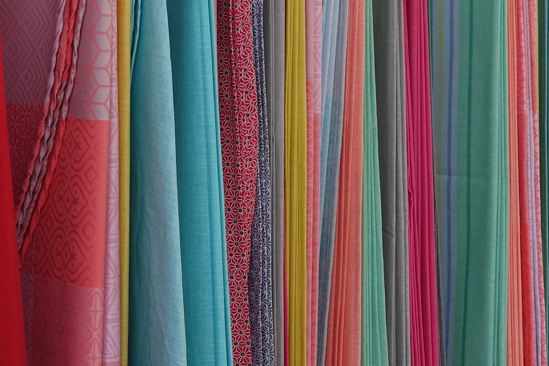 a bunch of different colored fabrics hanging on a wall