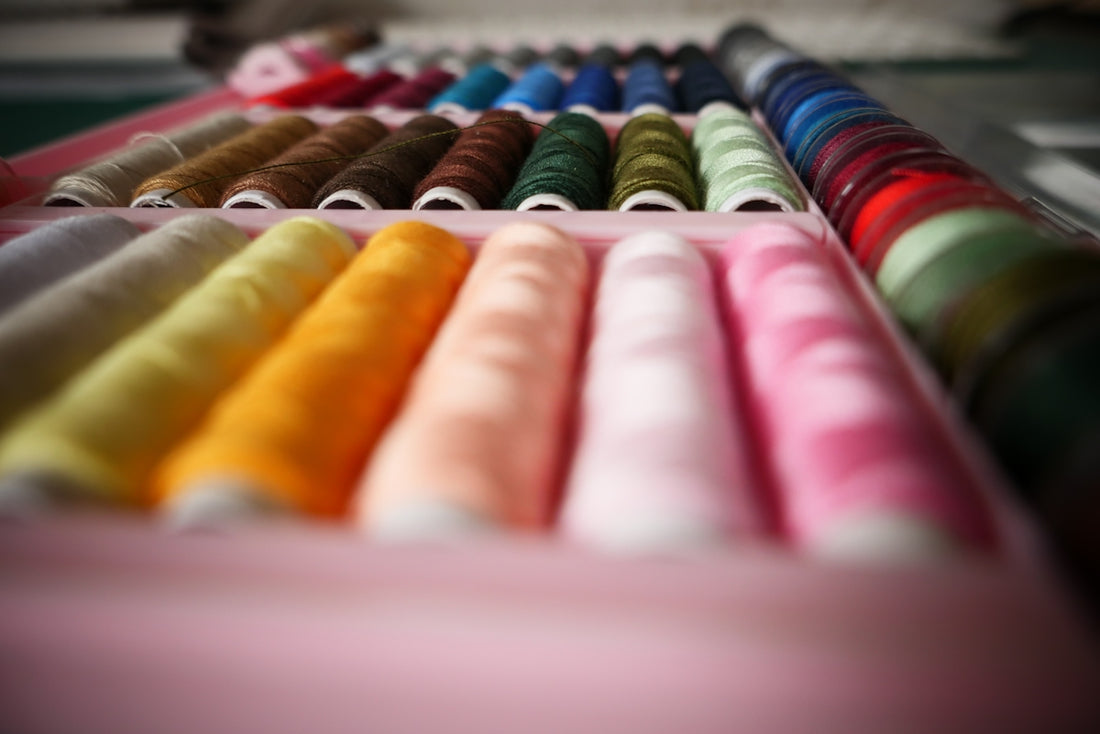 a row of different colored spools of thread