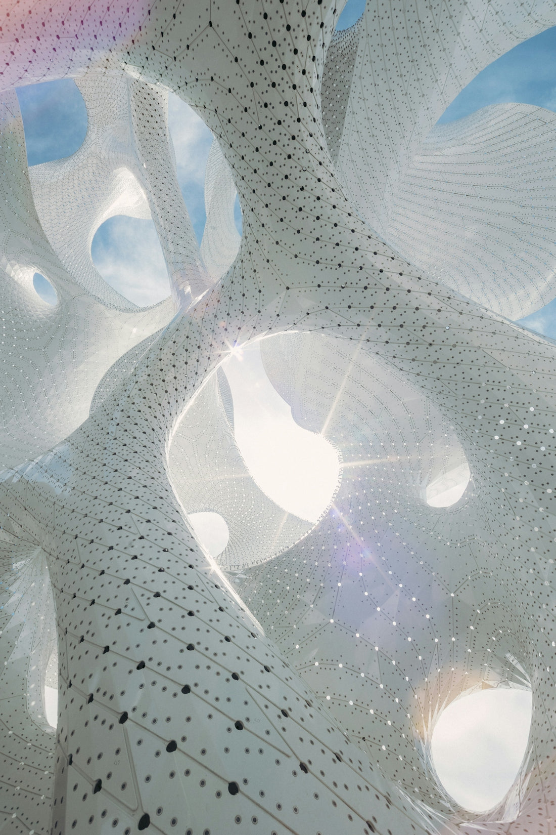 Abstract white structure with holes against the blue sky.