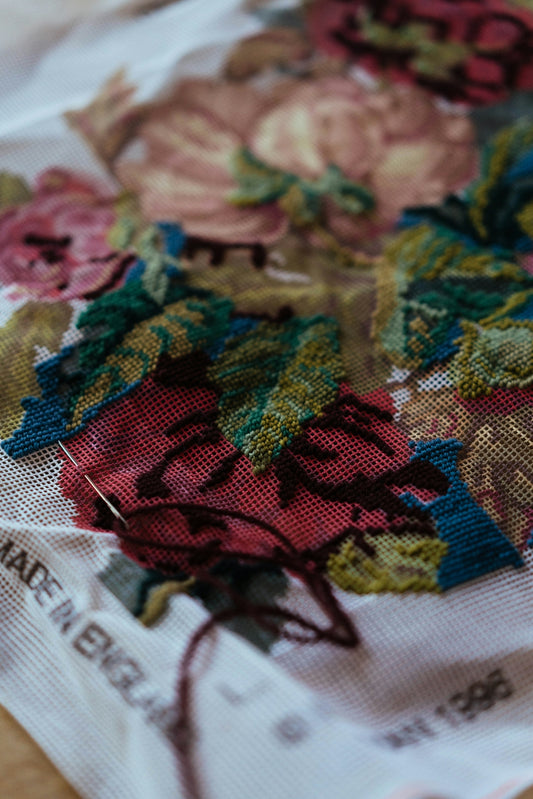 Embroidery of roses on white fabric with needle.