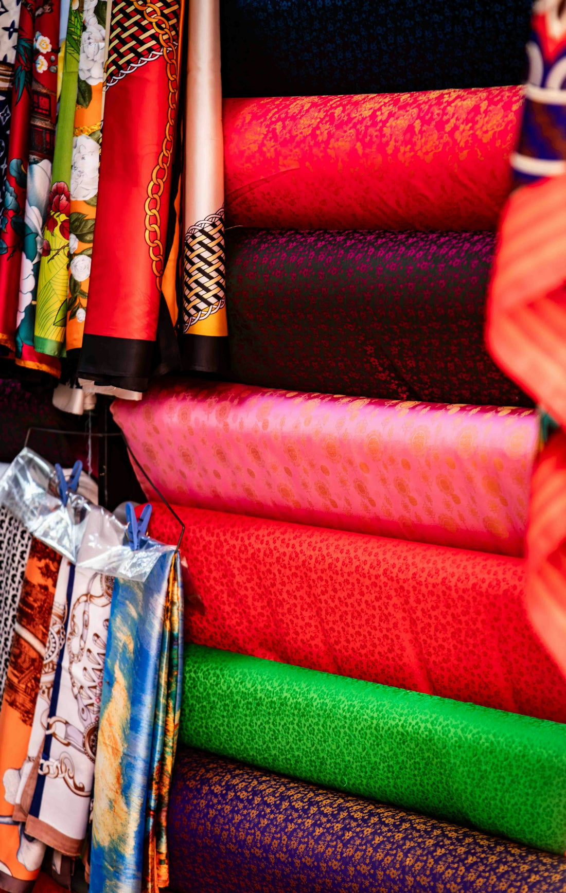 Stacks of colorful patterned fabrics in a market.