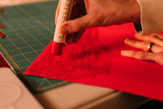 Person applying glue to red paper with a glue stick.