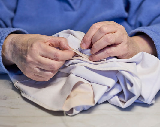 Hands carefully sewing a patch onto fabric.