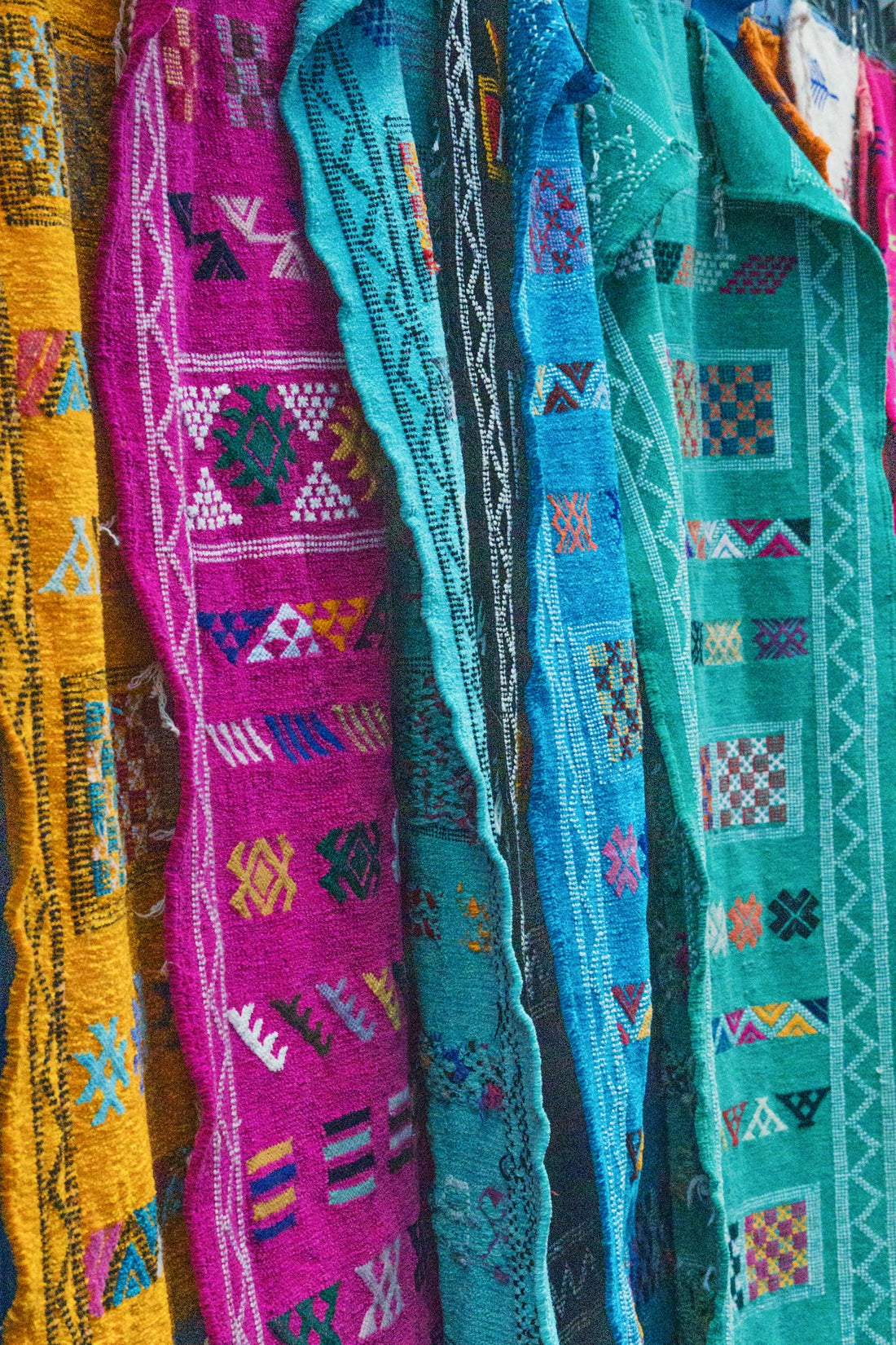 Colorful woven textiles with geometric patterns hang side-by-side.