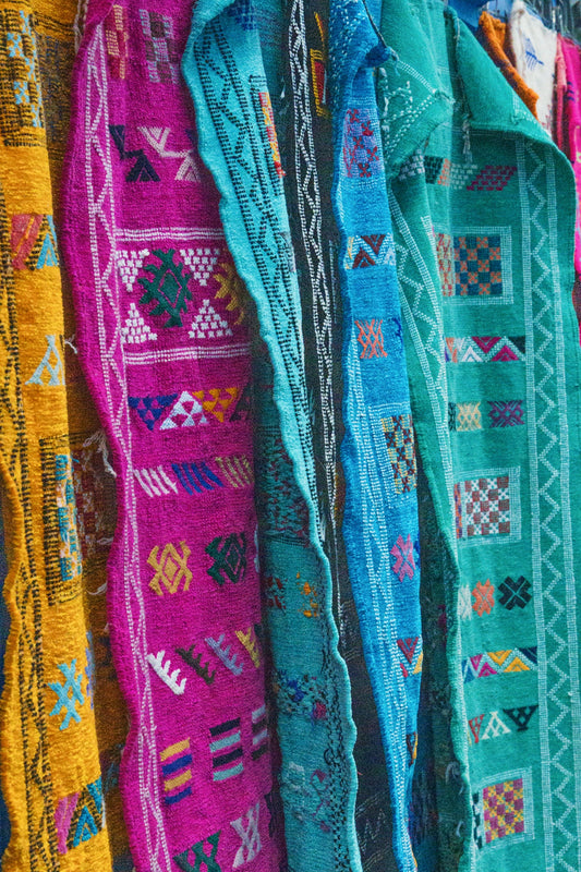 Colorful woven textiles with geometric patterns hang side-by-side.