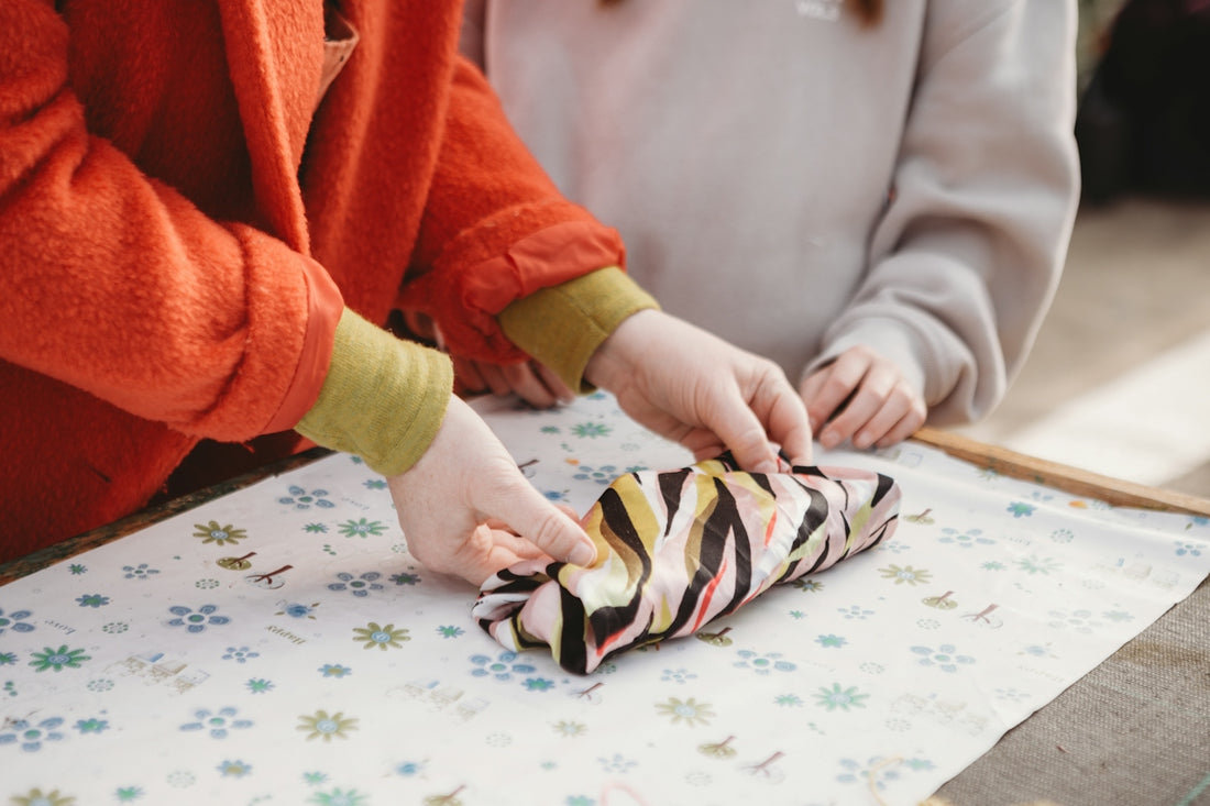 Hands wrapping an object in patterned fabric